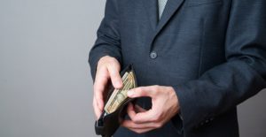 Businessman with money in purse in hands on a gray background